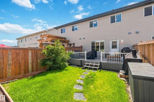 Private backyard featuring a wooden fence, manicured lawn with stepping stones, and a composite deck - 940 East Gate, Edmonton, AB 