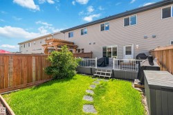 Private backyard featuring a wooden fence, manicured lawn with stepping stones, and a composite deck - 