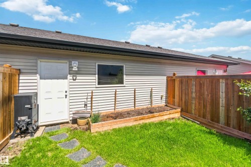 Manicured lawn with a raised garden bed and stepping stone pathway - 940 East Gate, Edmonton, AB 