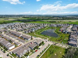 Aerial perspective showcasing a residential community with a central pond and green spaces - 