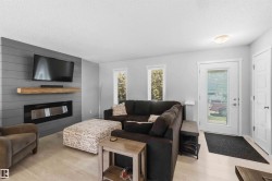 Living area featuring wood-finish flooring, a contemporary electric fireplace with a wood mantle, and a shiplap accent wall - 