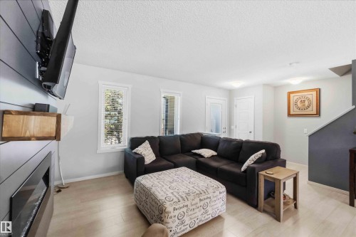 Living area featuring light wood-finish flooring, white walls, and a shiplap accent wall - 940 East Gate, Edmonton, AB 