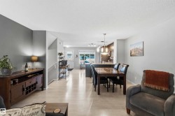 Open-concept living space featuring light wood-finish flooring, a dining area with a dark wood table, and a kitchen with an island and pendant lighting - 