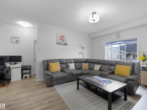 Bright living space featuring wood-finish flooring, white walls, and two ceiling-mounted light fixtures - 415 2203 44 Ave, Edmonton, AB 
