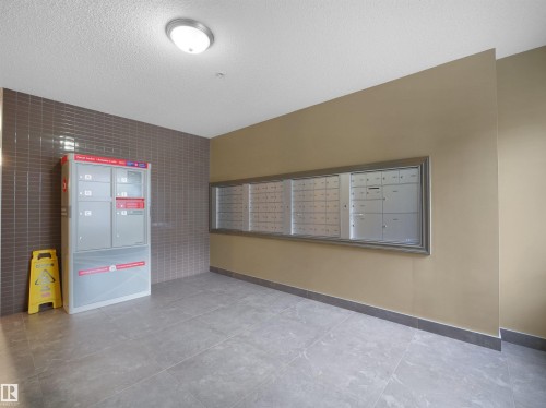 Foyer area featuring tile flooring, a mounted light fixture, and two walls with horizontal tile accents - 415 2203 44 Ave, Edmonton, AB 