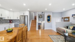 Open-concept interior featuring wood-finish flooring, white cabinetry, stainless steel appliances, and recessed lighting - 