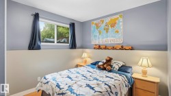 Bedroom featuring a multi-pane window with dark curtains, two-tone wall paint, and wood-finish flooring - 