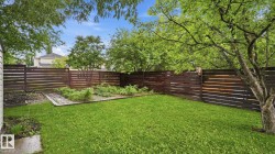 Expansive backyard featuring a manicured lawn, established garden beds, and a perimeter fence with horizontal wood panels - 