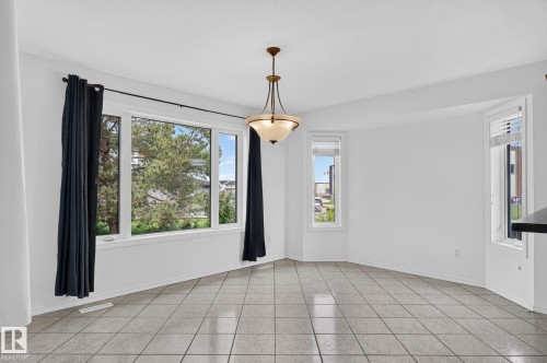 Bright interior space featuring a multi-pane window, two bay windows, and tile flooring - 86 Heritage Crescent, Stony Plain, AB 