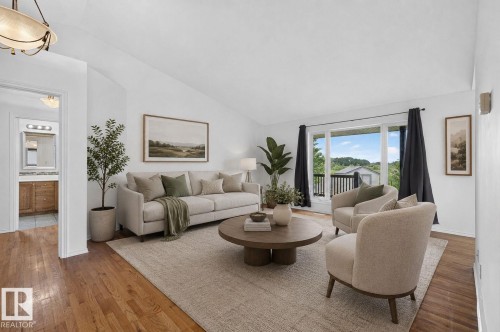 Spacious living area featuring vaulted ceilings, wood-finish flooring, and direct access to an outdoor balcony - 86 Heritage Crescent, Stony Plain, AB 
