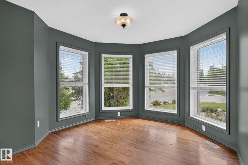 Bay window area with five large windows, wood-finish flooring, and a ceiling-mounted light fixture - 86 Heritage Crescent, Stony Plain, AB 
