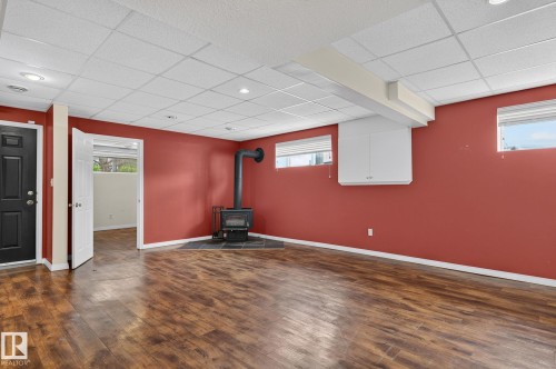 Spacious interior with vinyl flooring and a corner wood-burning stove - 86 Heritage Crescent, Stony Plain, AB 