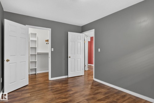 Interior space featuring wood-finish flooring, two white paneled doors, and gray painted walls - 86 Heritage Crescent, Stony Plain, AB 