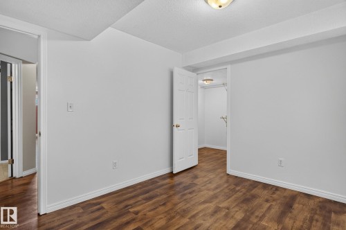 Room featuring wood-finish flooring, white baseboards, and a white ceiling with an overhead light fixture - 86 Heritage Crescent, Stony Plain, AB 