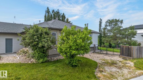 Rear exterior featuring a grey shingle roof, light brick siding, and a rear entry door - 86 Heritage Crescent, Stony Plain, AB 