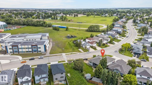 Aerial perspective showcasing a suburban setting with residential properties, a large institutional building, and expansive green spaces - 86 Heritage Crescent, Stony Plain, AB 