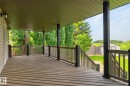 Expansive covered deck featuring wood-finish decking and dark wood railings - 86 Heritage Crescent, Stony Plain, AB 