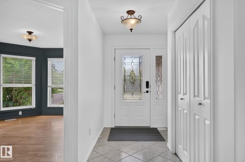 Foyer featuring leaded glass entry door with sidelight, tile flooring, and bi-fold closet doors - 86 Heritage Crescent, Stony Plain, AB 