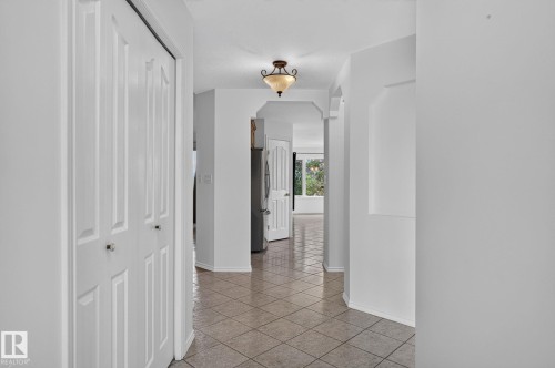 Hallway featuring diagonal tile flooring, white bi-fold doors, a semi-flush mount ceiling light fixture, and arched wall niches - 86 Heritage Crescent, Stony Plain, AB 