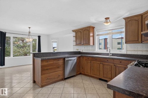 Kitchen featuring wood cabinetry, stone-finish countertops, and a tile backsplash - 86 Heritage Crescent, Stony Plain, AB 