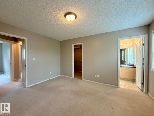 Carpeted room featuring a ceiling-mounted light fixture and neutral-toned walls - 12207 16 Avenue, Edmonton, AB 