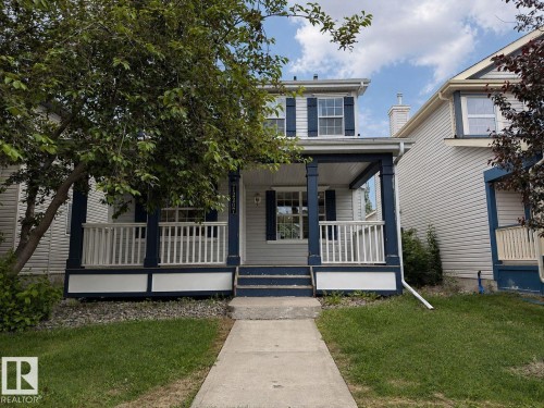 Two-story residence featuring a covered front porch with white railings and blue columns, horizontal siding, and functional dark blue window shutters - 12207 16 Avenue, Edmonton, AB 