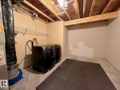 Dedicated laundry area featuring a concrete floor and a wire shelving unit - 12207 16 Avenue, Edmonton, AB 