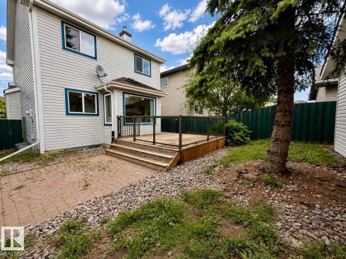 Rear exterior featuring light-colored siding and blue window trim - 12207 16 Avenue, Edmonton, AB 