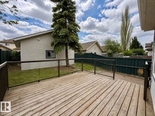 Expansive wood-finish deck with glass panel railing and brown metal posts - 12207 16 Avenue, Edmonton, AB 