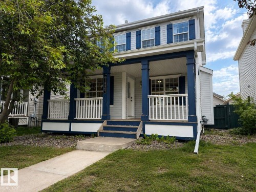 Two-story residence featuring a covered front porch with white railings, blue columns, and matching blue shutters - 12207 16 Avenue, Edmonton, AB 