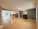 Open-concept living space featuring wood-finish flooring, a stone-clad fireplace with a white mantel, and recessed lighting - 12207 16 Avenue, Edmonton, AB 