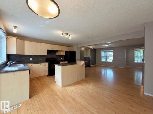 Open-concept kitchen and living area featuring wood-finish flooring - 12207 16 Avenue, Edmonton, AB 