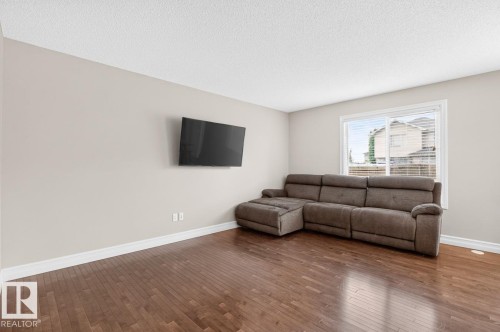 Spacious room featuring wood-finish flooring, neutral wall paint, and white baseboards - 12032 167B Avenue, Edmonton, AB 