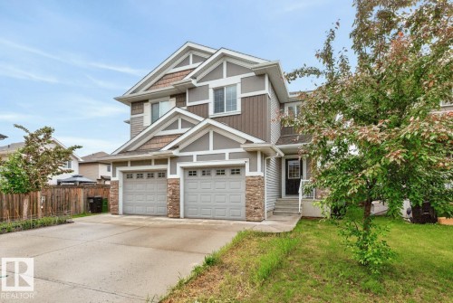 Two-story residential exterior featuring a two-car garage, stone accents, horizontal and shake siding, and a concrete driveway - 12032 167B Avenue, Edmonton, AB 