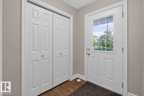 Entryway featuring a white paneled door with windowpanes, light gray wall paint, white trim, and wood-finish flooring - 12032 167B Avenue, Edmonton, AB 
