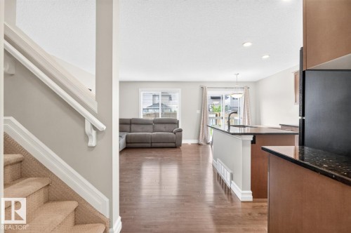 Open-concept living space featuring wood-finish flooring, recessed lighting, and a kitchen island with dark countertops - 12032 167B Avenue, Edmonton, AB 