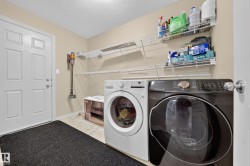 Dedicated laundry area featuring front-loading appliances, light-toned wall paint, and white wire shelving for organization - 