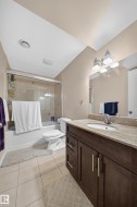 Contemporary bathroom featuring a dark wood-finish vanity with a light-toned stone countertop, an integrated sink, and a chrome faucet - 