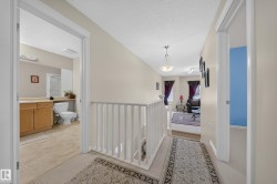 Upper-level hallway featuring neutral wall paint, white trim, and a classic white banister - 