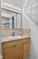 Vanity featuring a light wood-finish cabinet with double doors and two drawers, a rectangular undermount sink, and a brushed nickel faucet - 