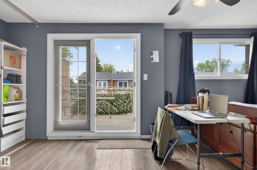 Light wood-finish flooring, a ceiling fan, and a built-in shelving unit characterize this room - 13445 40 Street Nw, Edmonton, AB 