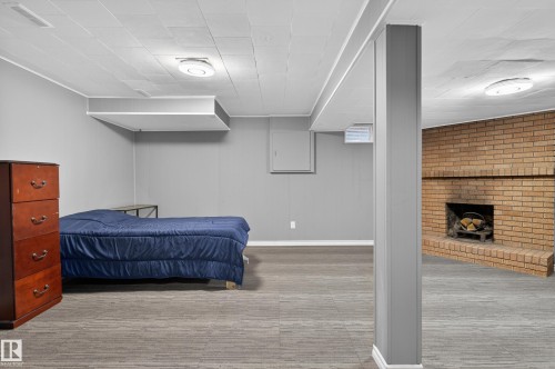 Spacious interior featuring a brick fireplace, grey walls, and carpet tile flooring - 13445 40 Street Nw, Edmonton, AB 