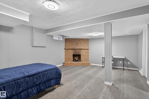 Spacious room with a brick fireplace, grey walls, and wood-finish flooring - 13445 40 Street Nw, Edmonton, AB 