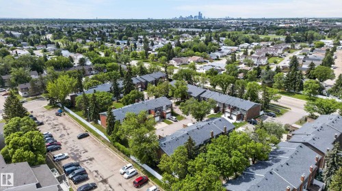 Aerial perspective showcasing multiple townhouse-style buildings with dark shingle roofs and brick facades - 13445 40 Street Nw, Edmonton, AB 