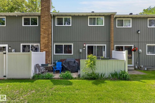 Rear exterior featuring vertical siding, multiple windows, and a brick chimney - 13445 40 Street Nw, Edmonton, AB 