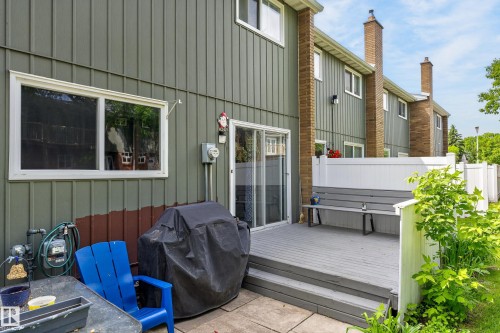 Rear exterior featuring a gray deck with built-in bench seating, white vinyl privacy fencing, and sliding glass door access - 13445 40 Street Nw, Edmonton, AB 