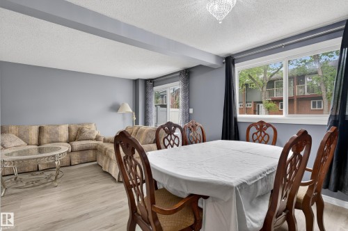 Dining area featuring a crystal chandelier, large window, and wood-finish flooring - 13445 40 Street Nw, Edmonton, AB 