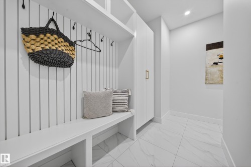 Built-in white mudroom bench with cubby storage, vertical slat wall paneling, and integrated hooks - 372 Creekside Green, Leduc, AB 