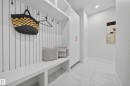 Built-in white mudroom bench with cubby storage, vertical slat wall paneling, and integrated hooks - 372 Creekside Green, Leduc, AB 