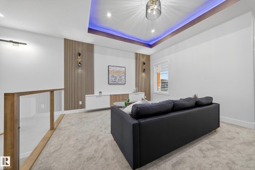 Recessed ceiling with blue accent lighting and a contemporary chandelier - 372 Creekside Green, Leduc, AB 